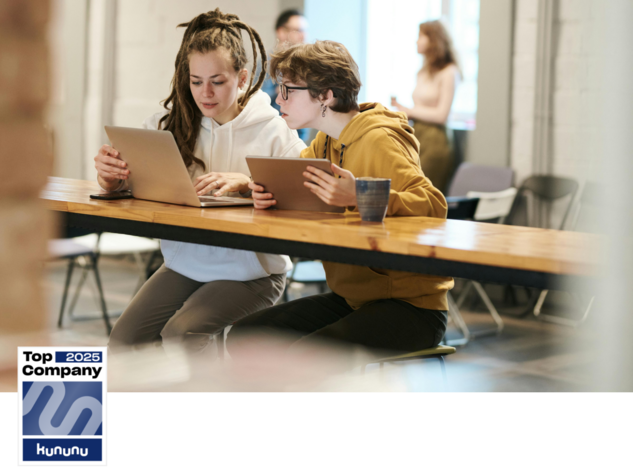 Zwei junge Menschen mit Laptop und Tablet unterhalten sich, zusätzlich wird die Auszeichnung Top Company 2025 von Kununu angezeigt