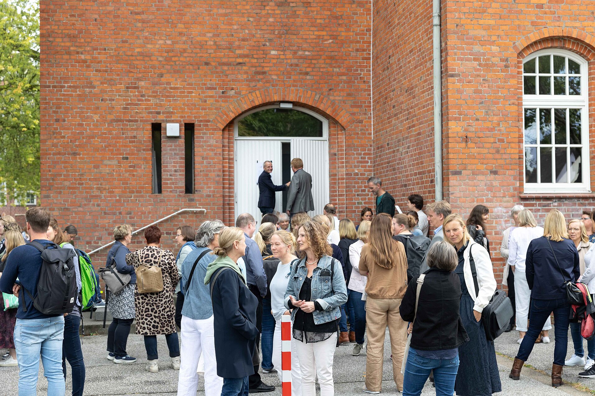 Menschen stehen in kleinen Gruppen vor einer Kirche und unterhalten sich