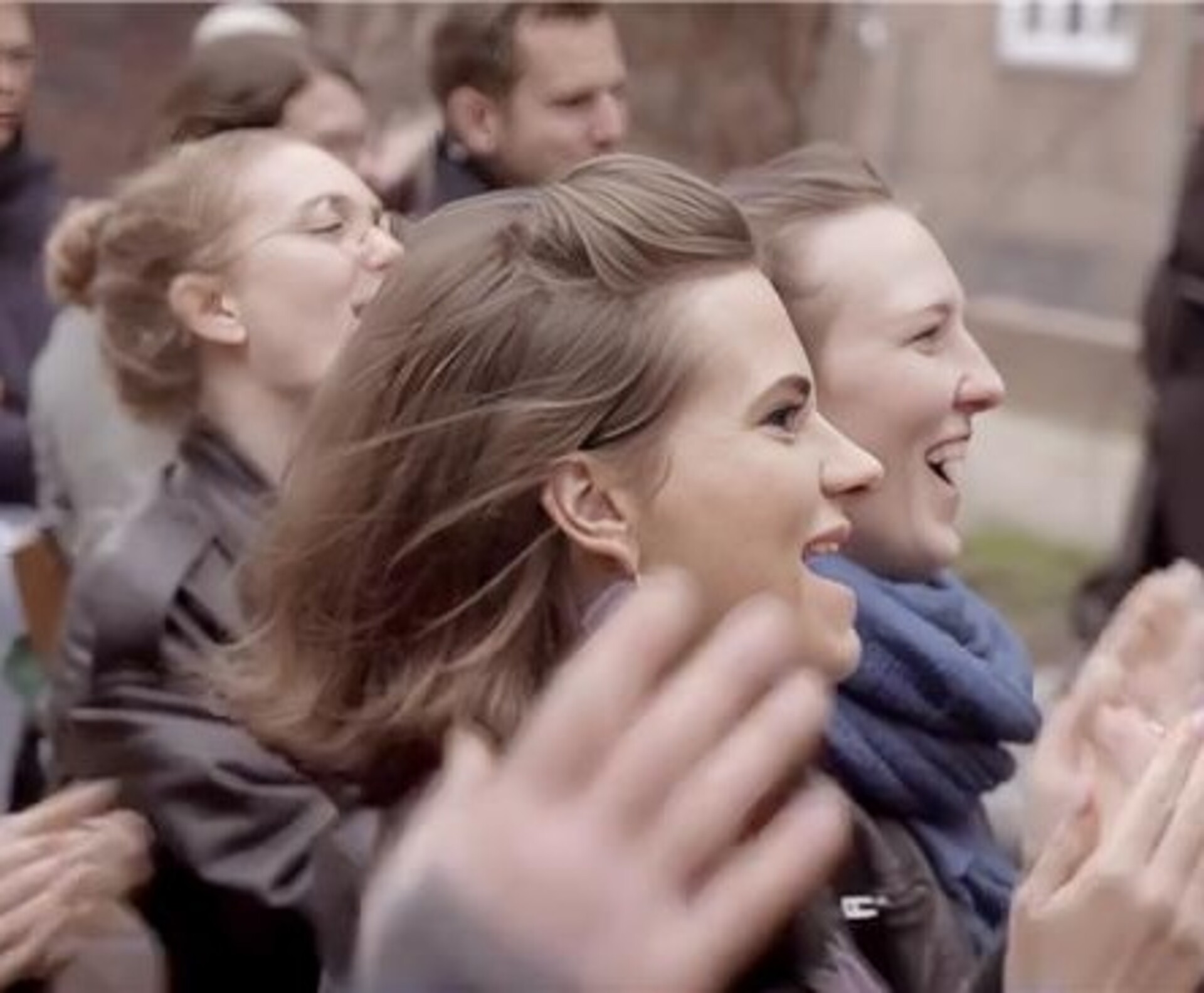 Das Bild zeigt vier Personen im Publikum, die klatschen und sich freuen.